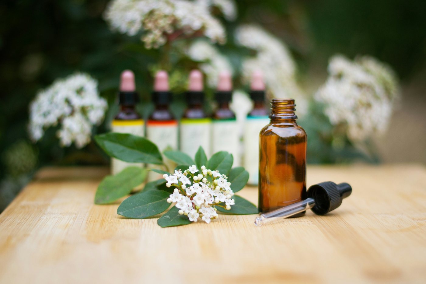 Flacon ambré à compte-gouttes et fleurs blanches sur une table en bois